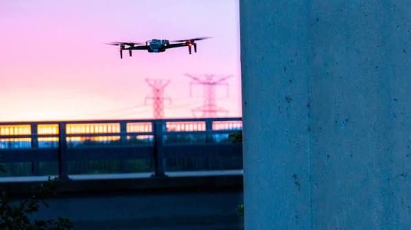Drone in flight at dusk near transmission towers.